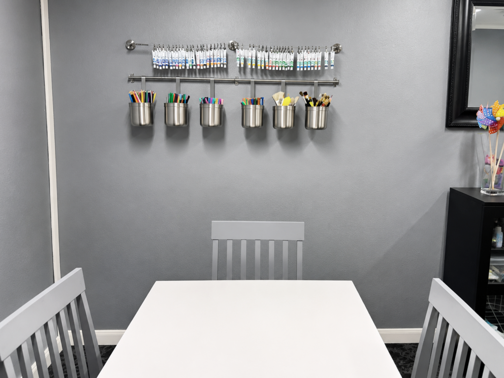Art therapy work table with markers organized on a wall rail at MBHI in Dallas